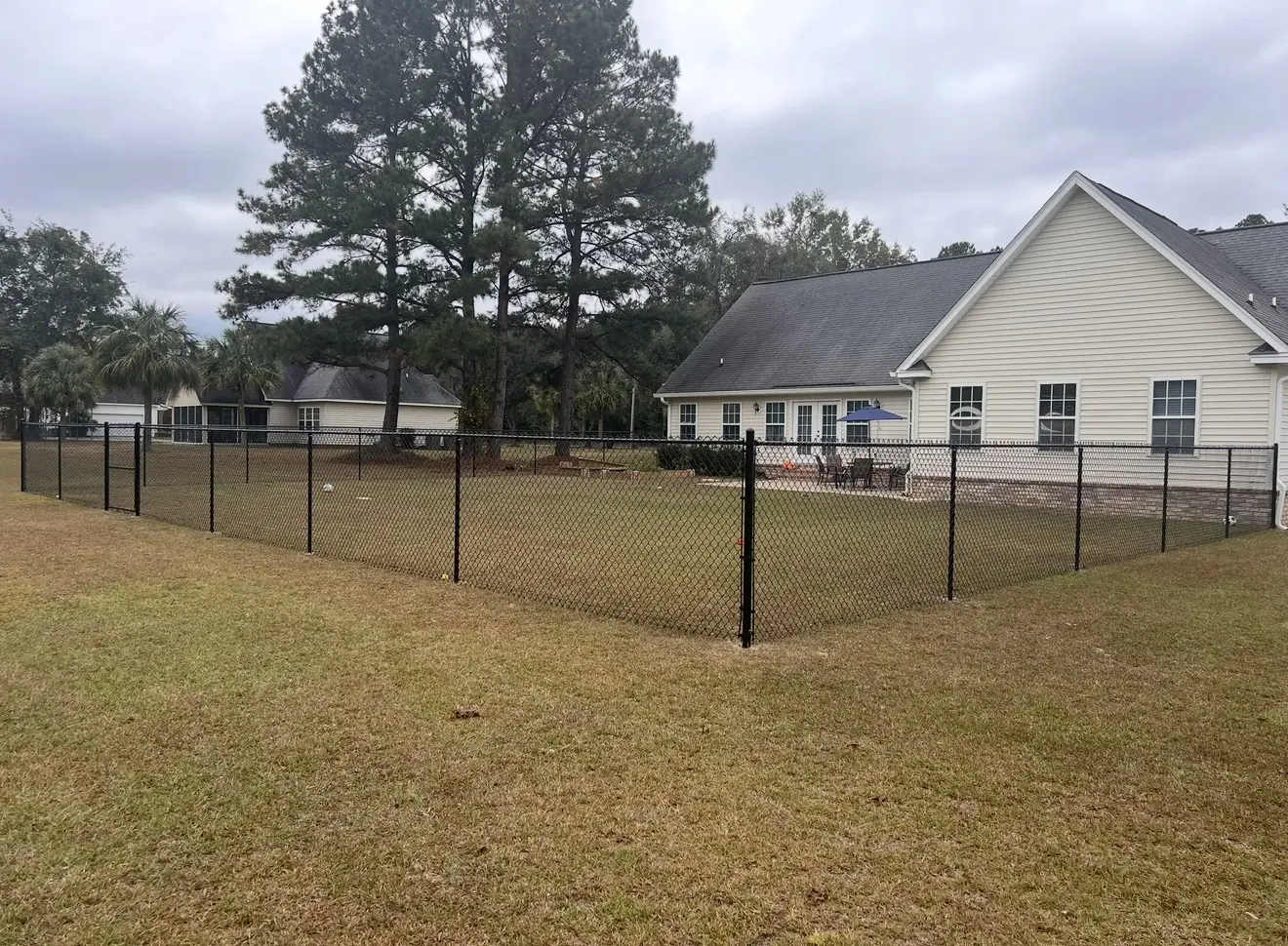 Black-coated chain-link fence enclosing a large residential lawn