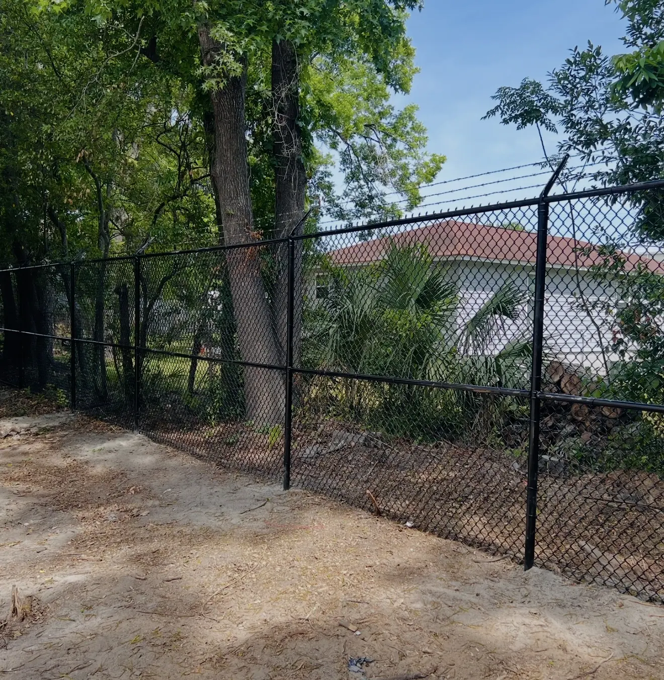 Tall black commercial chain-link security fence with barbed-wire top installed in Downtown Savannah