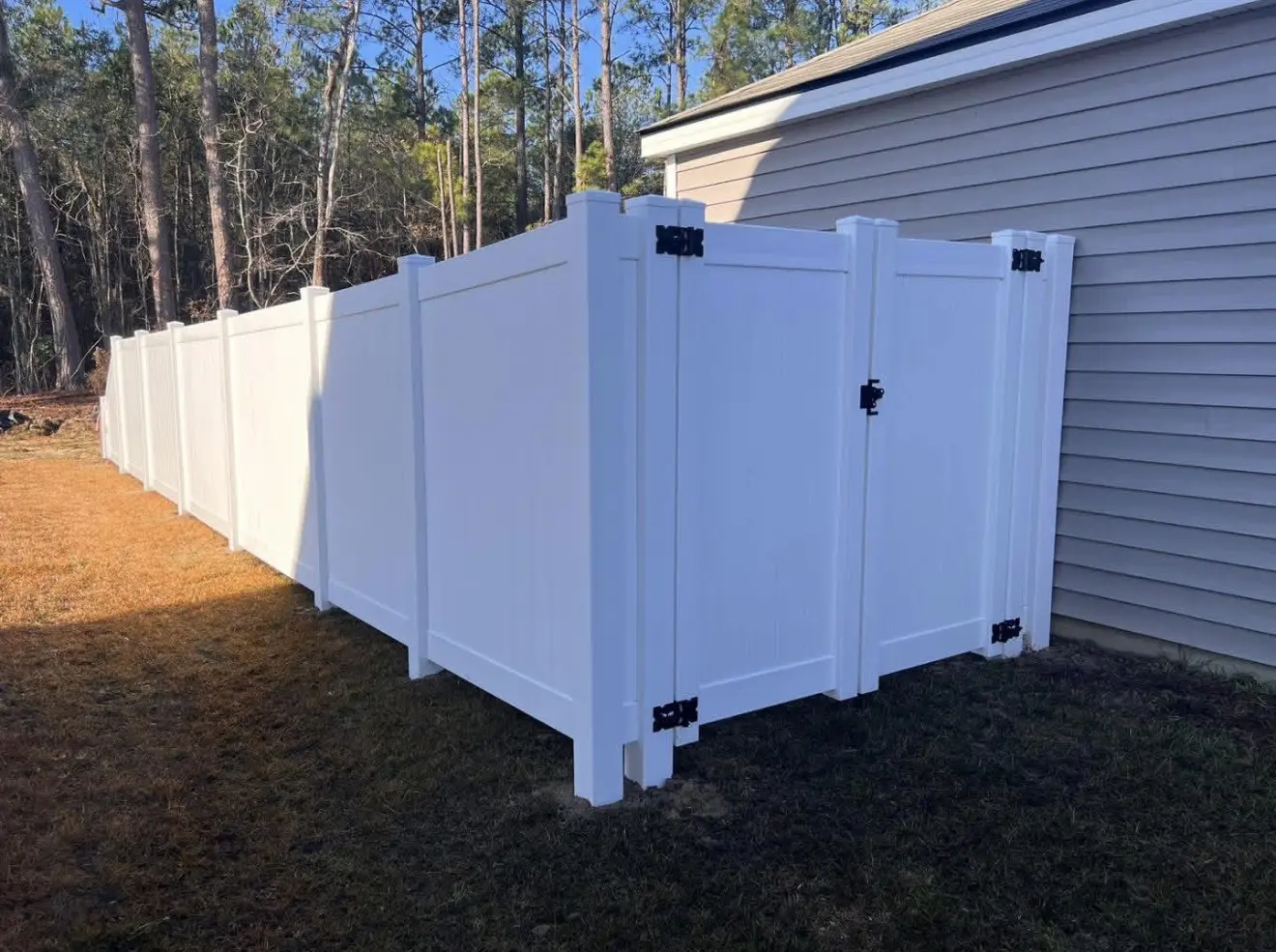 White vinyl privacy fence with a matching walk gate beside a gray home