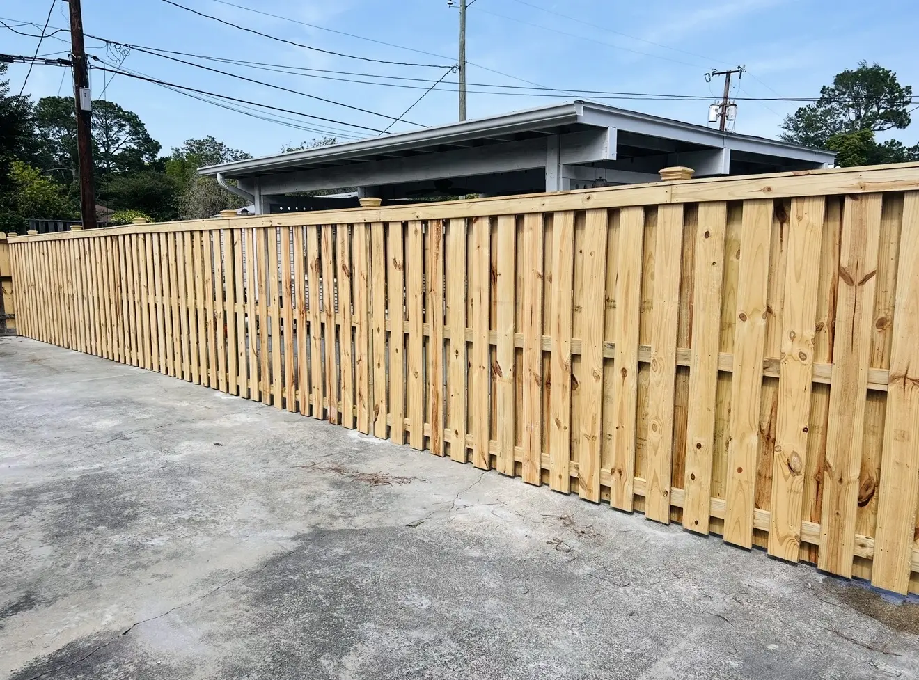 Pressure-treated cap-and-trim wood fence following a commercial driveway
