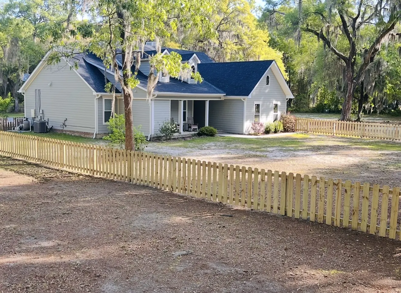 Natural wood picket fence framing the front yard of a cottage-style home