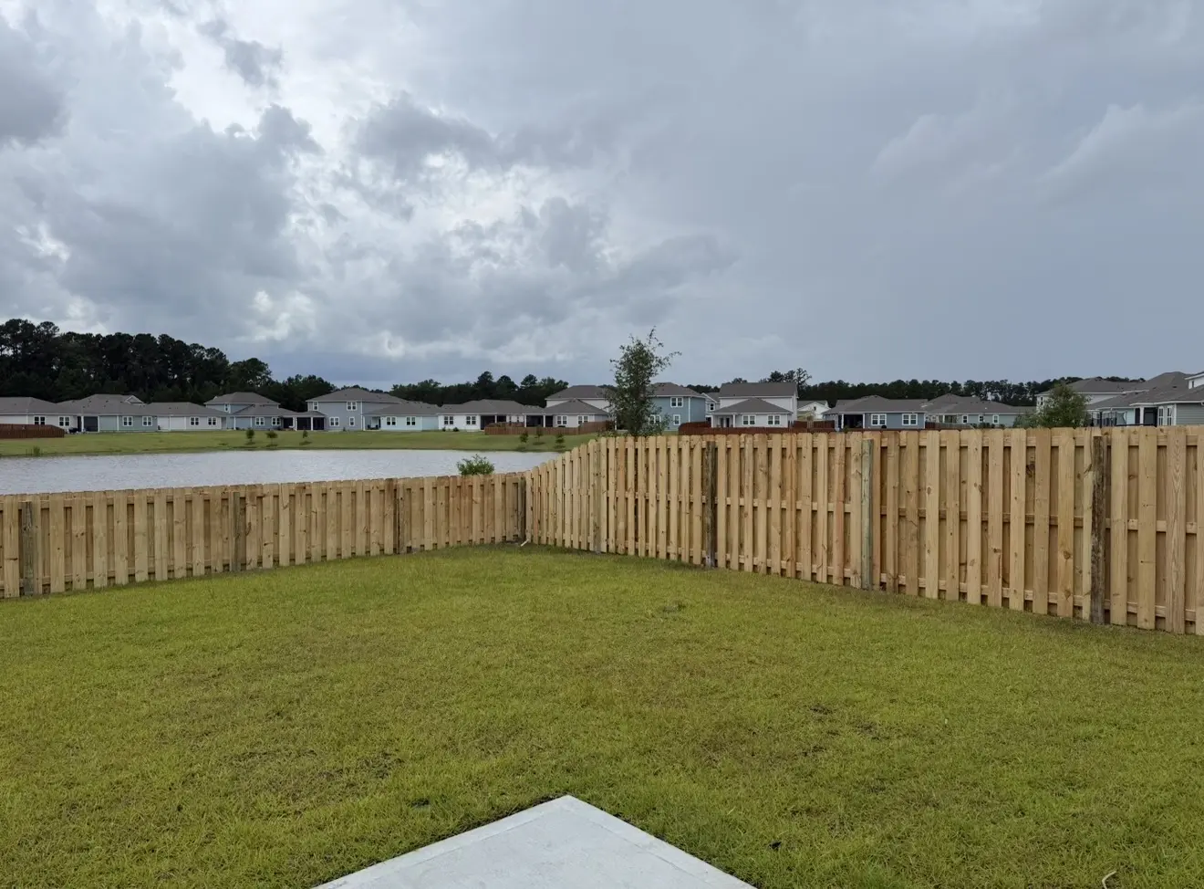 Pressure-treated shadowbox fence following a residential yard beside a lagoon